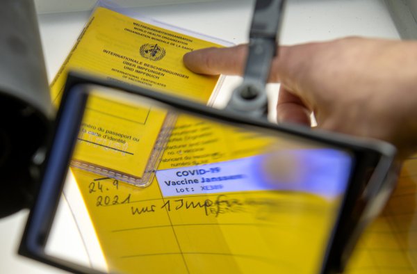 Bei der Kriminalpolizeiinspektion liegen Impfpässe unter einer Lupe, darunter ein aufgeschlagener Impfausweis. - © Symbolbild: Stefan Puchner/dpa