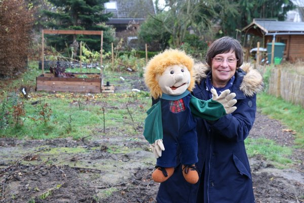 Pfarrerin Martina Stecker mit Handpuppe Felix im Zukunftsgarten hinter ihrem Wohnhaus. - © Alexandra Schaller
