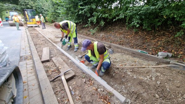 Die Arbeiter verlegen Glasfaser unter dem kombinierten Geh- und Radweg an der Lemgoer Straße (B66) in Dörentrup. In einem Rutsch wird das Pflaster neu gemacht. - © Nadine Uphoff