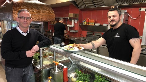 Yol-Chef Serafettin Yilmaz reicht Dennis Bernat von der Heilpädagogisch-therapeutischen Einrichtung Grünau einen Teller mit Essen. Am kommenden Mittwoch gehen alle Gewinnen aus dem Tagesverkauf an die Einrichtung. - © Sven Kienscherf