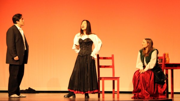 Carmen (mittig im Bild, Yezitong Fang) imponiert Don José (Taesung Lee) und macht damit seine Jugendliebe Micaëla (Christin Stanowsky) eifersüchtig. - © Chiara Wibbeke