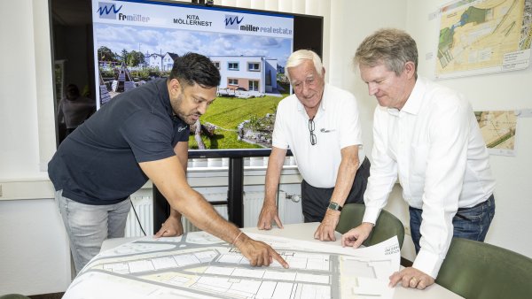 Projektleiter Manusch Varatharajah, Senior-Chef Peter von Möller und Möller-Real-Estate-Geschäftsführer Dennis Rauhut (v. l.) beugen sich über die Baupläne. - © Jörg Dieckmann