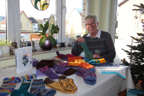 Karin Foerster zeigt Strick- und Stickgeschenke, die die Damen im Handarbeitskreis der AWO Lage erstellt haben. - © Cordula Gröne