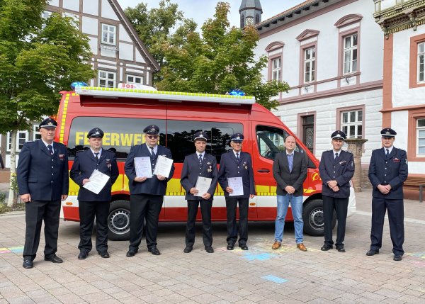 Feuerwehr-Chef Joachim Hartfelder, die Geehrten Maik Lohmeier-Feuerwehrchef Joachim Hartfelder, Maik Lohmeier-Schaeffer, Markus Rißmann, Marcel Blinne, Edgar Finke, Bürgermeister Christoph Dolle sowie die stellvertretenden Wehrführer Heiko Mühlenmeier und Cord Finke (von links) vor dem neuen Einsatzwagen am Rathaus. - © brink-medien