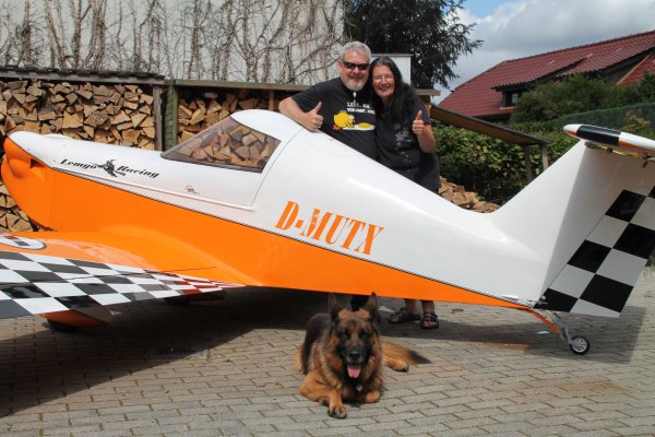 Fast täglich hebt Thomas ab. Auch seine Frau Anke nimmt er mit in die Lüfte. Hund „Luis" liegt gemütlich vor dem Ultraleichtflugzeug, dass Thomas selbst gebaut hat. - © Judith Stracke