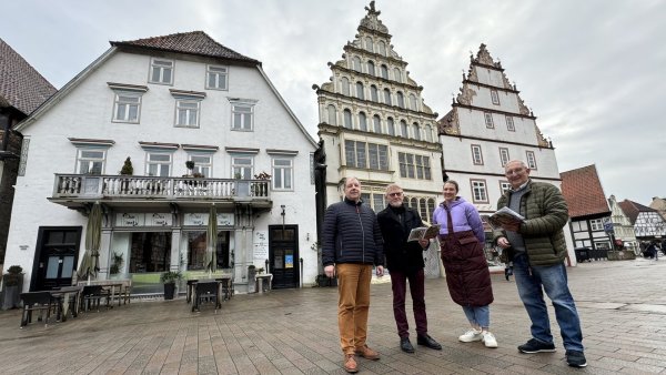 Stefan Wiesekopsieker (von links, Lippischer Heimatbund), Autor Walter Theiler, Inga Bernhard (Stadtarchiv) und Dieter Homann vor drei Gebäude am Markt, die einst der Familie Barkhausen gehörten. - © Sven Kienscherf