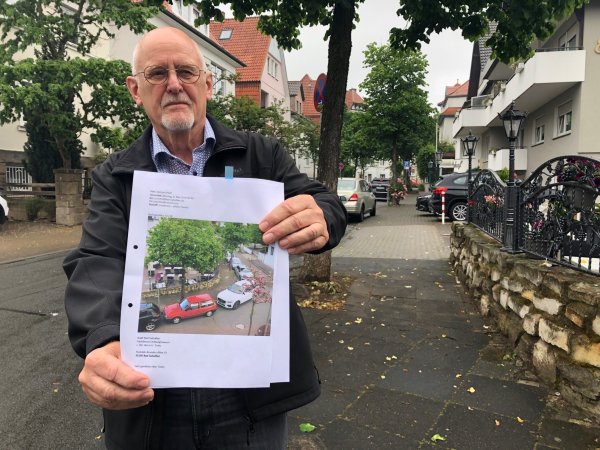 Michael Pfaff zeigt in der Freidenstraße ein Foto, was er gemacht hat und dass seine Parksituation in der kleinen Straße zeigt. Er fürchtet, dass die Feuerwehr im Ernstfall nicht mehr durchkommt. - © Sven Kienscherf