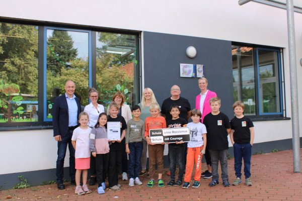 Pastor Dr. Bartolt Haase (ehemaliger Vorstandsvorsitzende Eben-Ezers, von links), Beate Busse (Schulleiterin), Sabine Menzel (Bereichsleitung Kinder und Jugendliche), Rahel Neufeld (stellvertretende Schulleiterin), Dr. Frank Oliver Klute (Regionalkoordinator), Maike Krüger (Mitglied der Geschäftsführung Eben-Ezer) und Grundschüler freuen sich über das Zertifikat "Schule ohne Rassismus - Schule mit Courage". - © Chiara Wibbeke