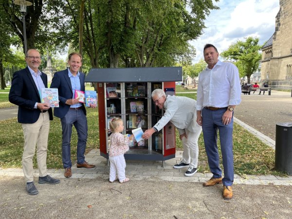 Weihen den Bücherschrank ein: Peter Karaski (Hilfswerk des Lions Club Detmold-Residenz), Kay Sandmann-Puzberg (Vorstandsvorsitzender der Bürgerstiftung Detmold), die zweijährige Flora, Martin Christian Vogel (Hilfswerk des Lions Club Detmold-Residenz) und Frank Hilker (Bürgermeister der Stadt Detmold, von links). - © Elia Böckelmann