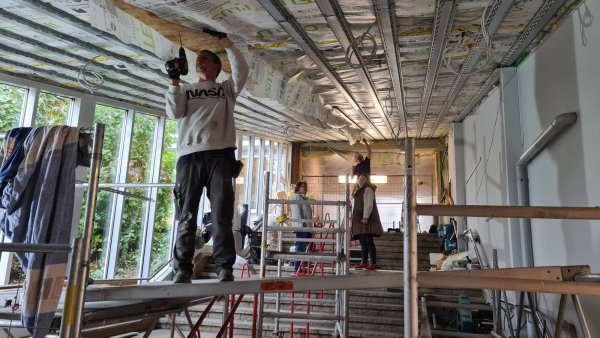 Christian Speck (vorne) und Jörg Hartwich sind mit den Arbeiten am Dach des Treppenhauses der Grundschule Ost beschäftigt, während Ingrid Behlen (links) von der Gemeinde Dörentrup und Architektin Andrea Nolting über den Fortschritt sprechen. - © Nadine Uphoff