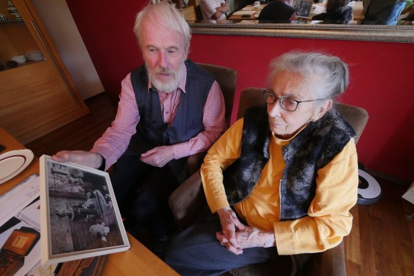 Ernst und Margret Nölke schauen sich ein Foto an, auf dem die Kinder von Lehrer Ernst Lütchemeier 1913 auf der Veranda des Schulhauses auf der Kussel an dessen Rundfunkempfänger horchen. - © Jost Wolf