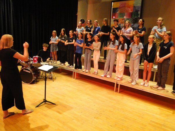 Die "Young Grabbe Voices" performen, unterstützt von Klavier und Schlagzeug, perfekt den Queen-Reißer "We Are the Champions" in der voll besetzten Schulaula des Grabbe-Gymnasiums. Das Publikum klatscht mit und schwenkt die Arme in jenem Rhythmus, den Musiklehrerin Stefanie Engelskirchen ihrem Chor als Dirigentin vorgibt. - © Hajo Gärtner