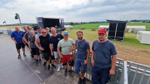 Die Helfer Andreas Bode (von links), Jens Bolte, Daniel Kohring, Torsten Mewes, Marcel Schulze mit dem kleinen Liam auf dem Arm, Marc Niehage, Michael Nolting, Robert Alwast, Sven Clauß und Andre Kotowski stehen auf dem Balkon der VIP-Area. Von hier aus gibt es einen tollen Blick auf die Bühne, die im Hintergrund noch den letzten Schliff bekommt. - © Nadine Uphoff