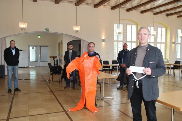 Bürgermeister Stefan Rother (vorne) zeigt einen einfachen Mundschutz der Firma Vorndamme (Isotemp), Heinz Blome (Ordnungsamt) einen orangen Schutzoverall. Im Hintergrund (von links) Rainer Holste (Ordnungsamt), Tim Sölter (Zentrale Dienste) und Stephan Beinker (Baubetriebshof/Feuerwehr). - © Dieter Asbrock