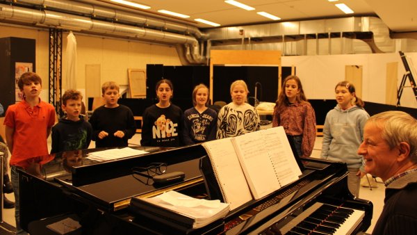 Friedrich (von links), Leopold, Ruben, Fatima, Julie, Mathilda, Pauline und Mariela trainieren ihre Stimme unter Anleitung des musikalischen Leiters Matthias Mönius (rechts) mit Gesangsübungen. - © Chiara Wibbeke