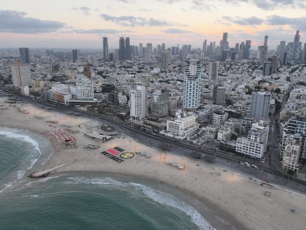 Aktivisten haben am Strand von Tel Aviv in Israel "War Kills Hostages" in großen Lettern in den Sand geschrieben. - © picture alliance / Anadolu