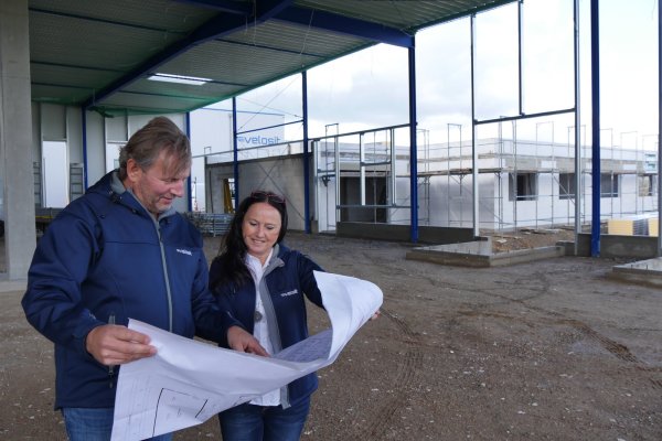 Firmeneigentümer Dr. Jens Hofele und seine Frau Sabine schauen sich gemeinsam die Pläne für die Velosit-Erweiterung im Industriepark Lippe an. Sie stehen in der Baustelle der Lagerhalle. Rechts davon entsteht ein Verwaltungstrakt. - © Jost Wolf