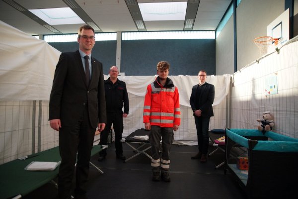 Bürgermeister Matthias Kalkreuter (links) und Diemo Dölle von der Stadt (rechts) bedanken sich bei Wehrführer Benjamin Brinkmeyer (Zweiter von links) und Elias Kübler vom Deutschen Roten Kreuz für den Aufbau in der Sporthalle am Werreanger. - © Stadt Lage