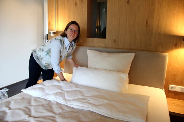 Die Zimmer sind so gut wie fertig: Tina Langner schüttelt schon einmal die Betten auf. Im August soll der Annenhof eröffnen. - © Kirsten Fuhrmann