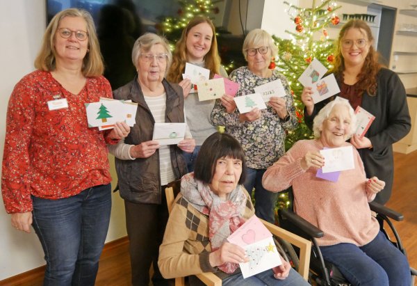 Ein weihnachtlicher Gruß für jeden: Die Bewohnerinnen freuen sich mit Hausleitung Sarah Köpel (rechts) und Melanie Beuke vom Begleitenden Dienst (links) über die viele Weihnachtspost der Schülerinnen und Schüler, die Lehrerin Nicole Burgard (hinten, Mitte) vorbeigebracht hat. - © Fotorechte: Diakonis