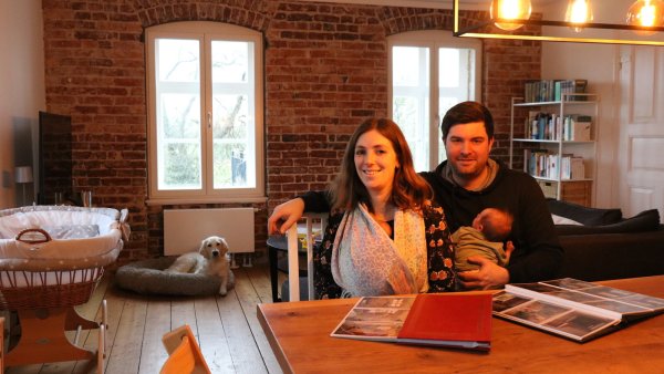 Jana und Marcel Stölting mit den gerade erst geborenen Zwillingen in ihrem kernsanierten Wohnzimmer mit Original-Backsteinwand. Im Hintergrund Hündin "Mira". - © Alexandra Schaller
