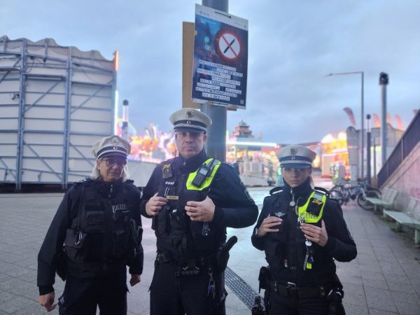 Polizeihauptkommissar Jens Solomon zeigt mit Polizeihauptkommissarin Sandra Niemeier (links) und Polizeikommissarin Sabrina Sundermann eines der Plakate kurz nach der Bahnhofsunterführung am Kronenplatz. 30 davon hängen nun im gesamten Stadtgebiet. - © Janet König