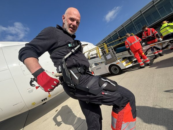 Markus Dransmann zeigt das Exoskelett. Druckfedern bewegen sich mit den Beinen und speichern Energie. Diese wird dann zur Platte vor der Brust umgeleitet, um den Rücken beim Vorbeugen zu entlasten. - © Jens Reddeker