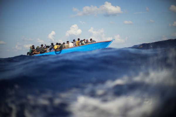Migranten sitzen in einem Holzboot im Mittelmeer nahe der Insel Lampedusa. - © Francisco Seco/AP/dpa