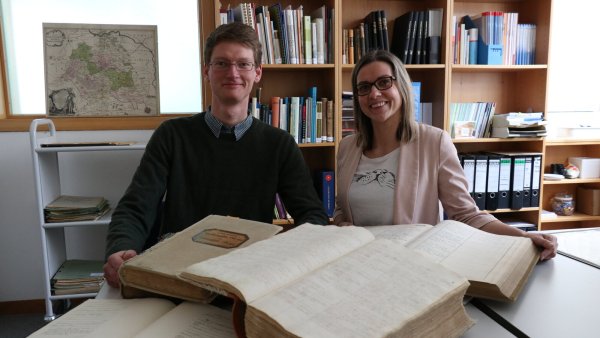 Die Archivare Katja Wiebe und Lars Sonnenberg mit einigen alten Kirchenbüchern und Dokumenten, die bei der Ahnenforschung helfen können. - © Alexandra Schaller