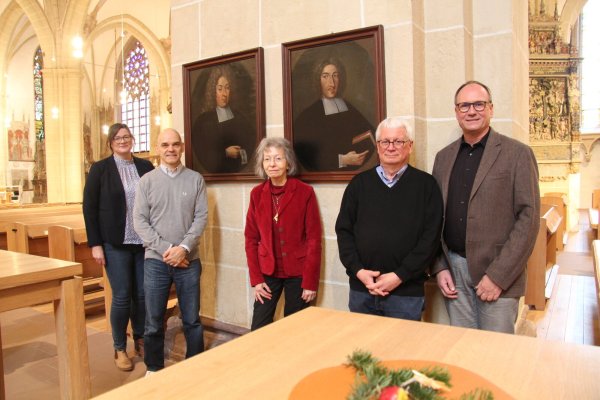Julia Kathke (von links) vom NHV, Designer Martin Emrich, die ehemalige Lemgoer Stadtarchivarin Gisela Wilbertz, der ehemalige Lemgoer Museumsleiter Jürgen Scheffler und Superintendent Dr. Andreas Lange vor den Porträts der ehemaligen Pfarrer Johann Barthold Haccius (links) und wahrscheinlich Andreas Haccius in der Kirche von St. Nicolai. - © Nadine Uphoff