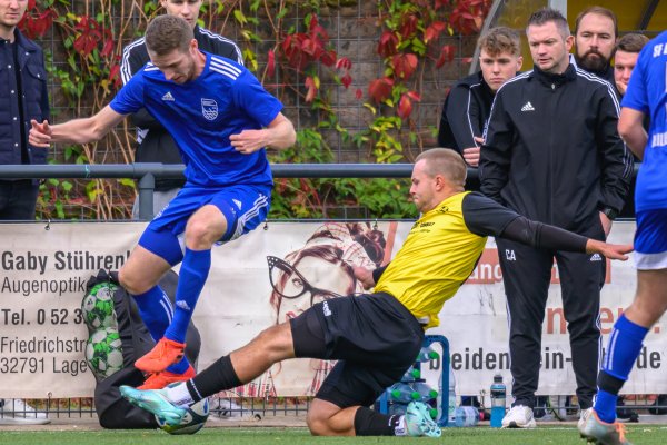 Steven Petrov vom FSV Pivitsheide (gelb) geht gegen Arne Seehricht von den SF Berlebeck-Heiligenkirchen resolut in den Ball. SF-Trainer Christopher André (rechts) beobachtet aufmerksam den Zweikampf. - © EGON PENNER