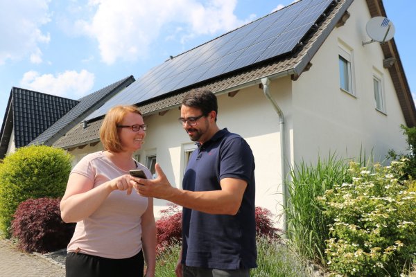 Jennifer Sonneborn und ihr Partner René Beermann prüfen auf dem Handy, was ihre PV-Anlage auf dem Dach im Hintergrund gerade an Strom produziert. - © Alexandra Schaller
