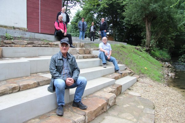 Es sitzen Paul Fait (vorne), Robert Masopust (rechts) und Fred Niemeyer auf den neuen Stufen am Waschplatz. Oben freuen sich (von links) Ulrich Ortmann, Ulla Golabeck, Nina Kunz und Reinhard Teuber über den neuen Ilsepark. - © Kirsten Fuhrmann(LZ)