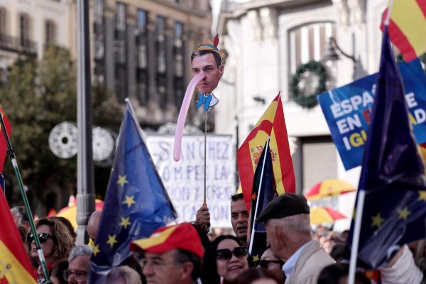 Ein Demonstrant hält am 12. November bei einer Demonstration in Madrid ein Bild des spanischen Premierministers Pedro Sánchez mit langer "Pinocchio"-Nase hoch. Foto: Thomas Coex / AFP - © AFP OR LICENSORS