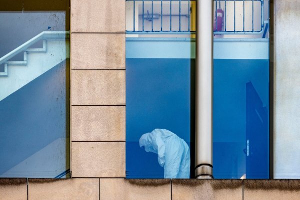 Eine Beamtin der Polizei untersucht in Schutzkleidung das Treppenhaus. - © Christoph Reichwein/dpa