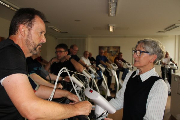 Kompetent: Ärztin Merhina Krivokapa gibt einem Herzpatienten auf dem Crosstrainer wertvolle Tipps, während ihr Kollege Andreas Matejek (hinten mit Brille) den Blutdruck misst. - © Ruben Honermeyer