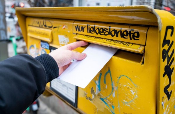 Ein Mann wirft einen Brief in einen Briefkasten. - © Christophe Gateau/dpa/Archivbild