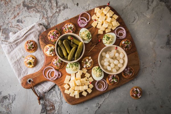 Eine typische niederländische Borrel-Platte mit Filet Americain auf Crackern mit Zwiebel, Ei oder Kapern. Dazu werden Käsewürfel, Cornichons, Silberzwiebeln und gefüllte Eier mit Schnittlauch serviert. - © Christin Klose/dpa-tmn