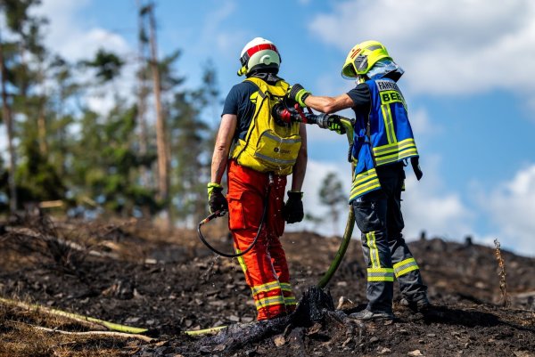 Mit Löschrucksäcken gehen die Feuerwehrleute etwa gegen Glutnester vor. - © Jacob Schröter/dpa