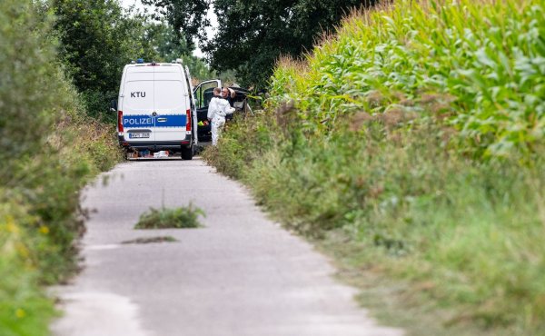 Ein Wagen der Kriminaltechnik steht an einem Maisfeld in Gronau. Hier wurden zwei Leichen gefunden. Die Identität der Opfer ist jetzt geklärt. (Archivfoto) - © Guido Kirchner/dpa