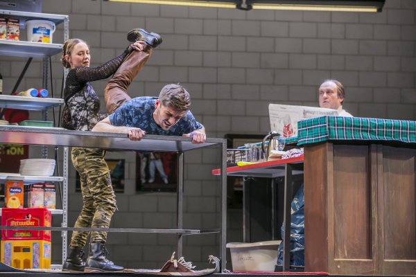 Das ist gut für die Bandscheibe: Lucia (Kathrin Berg) bei einer eigenwilligen Behandlung des geplagten Zinos (Adrian Thomser). Henry Klinder als Sokrates (rechts) schaut zu. - © Landestheater/Jochen Quast