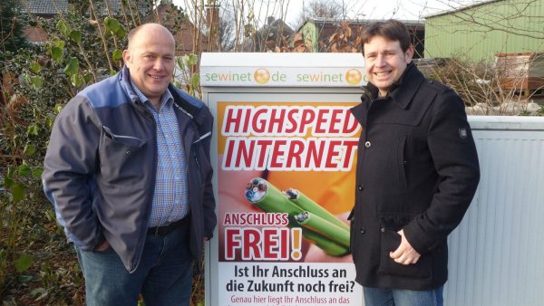 Es geht voran: Andreas Brinkmann (links) und Christian Kühnel stehen vor einem bereits errichteten Anschlusskasten der Firma Sewikom im Ortskern von Heipke. - © Privat