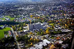 Die Bl&auml;tter der B&auml;ume haben sich herbstlich gelb verf&auml;rbt, der Kran hilft bei der Erweiterung des Klinikums.