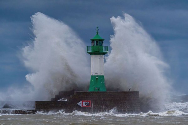 Wellen der Ostsee peitschen bei einem schweren Sturmtief an den Leuchtturm auf der Ostmole. Wegen des Sturmtiefs sind an der Ostseeküste Straßen und Uferbereiche vom Hochwasser überschwemmt worden. - © Georg Moritz/dpa