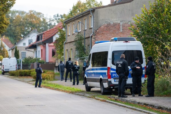 Polizisten stehen vor einem Grundstück in Herzberg. - © Christophe Gateau/dpa