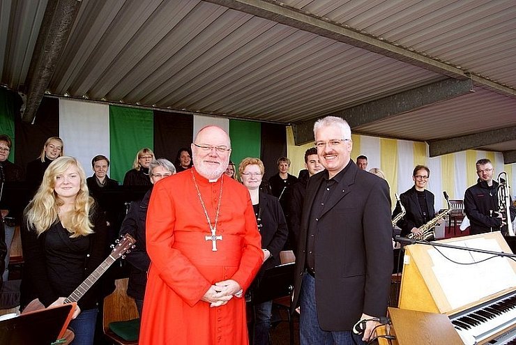 Alfons Haselhorst (r.) begrüßt beim Bundesschützenfest in Geseke Reinhard Kardinal Marx im roten Gewand. Im Hintergrund sind auf der großen Bühne die Musiker von newFACES zu sehen. - © FOTO: PRIVAT