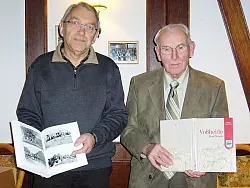 Stolz auf die Chronik: Heimatvereinsvorsitzender Gerd Habericht (links) und Autor Ernst Rehm schlagen ein druckfrisches Exemplar im Bergkrug auf. - © Foto: Fritzensmeier