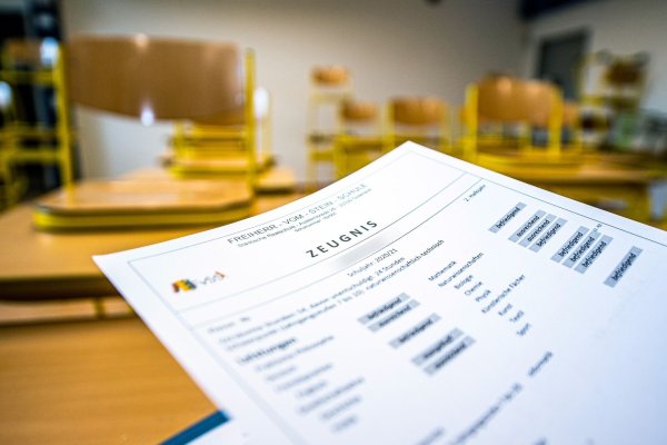 Eine Klassenlehrerin hält das Zeugnis eines Schülers hoch. - © David Inderlied/dpa/Archivbild