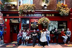 Die "Temple Bar" in Dublin mit einigen G&auml;sten, die vor der Bar etwas trinken und zusammensitzen. - &copy; Roland Marske/Jules Verne