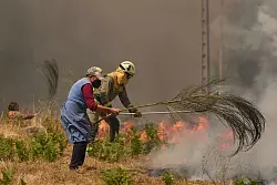 Einsatzkräfte, freiwillige Helfer und betroffene Anwohner kämpfen unermüdlich gegen die Flamen. - © Pablo Garcia/AP/dpa